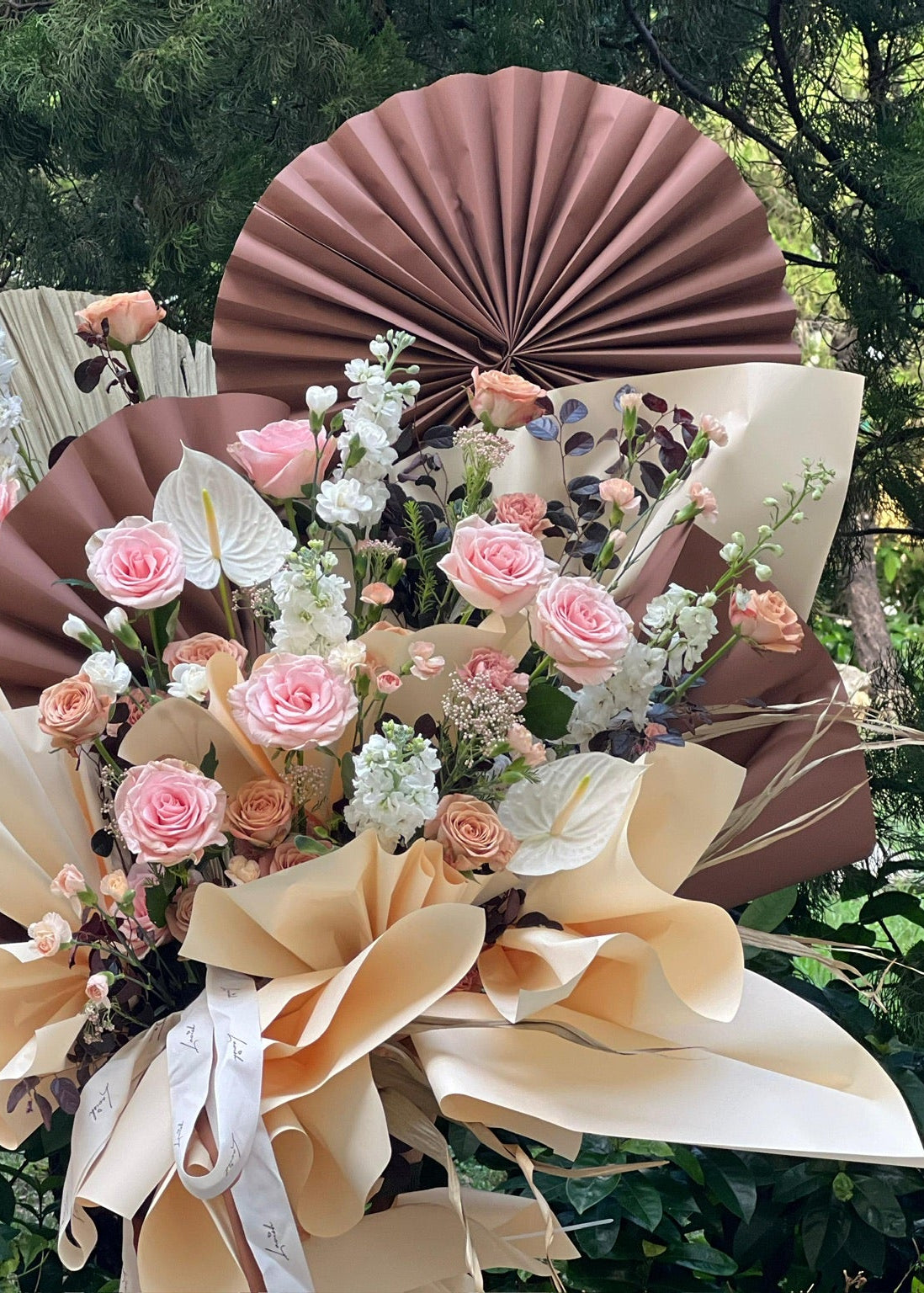 "Maroon Brew" grand opening flower stand designed by Lavish Florist, featuring a modern elegant arrangement of pink roses, Cappuccino roses, and delphiniums on a sleek black tripod—the perfect grand opening flower basket for boutique and shop launches.