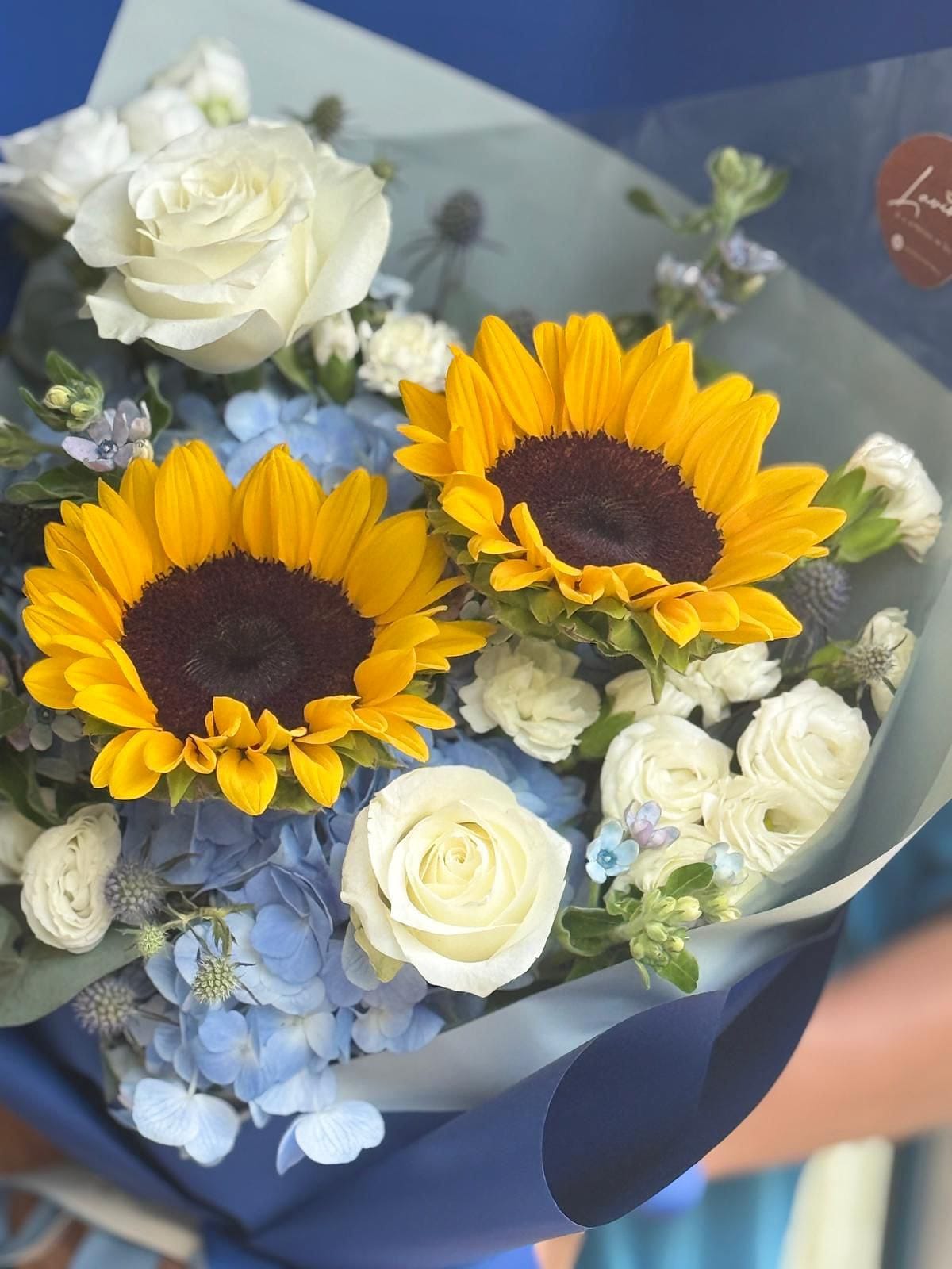 Bouquet of flowers with sunflowers and white roses on a blue surface