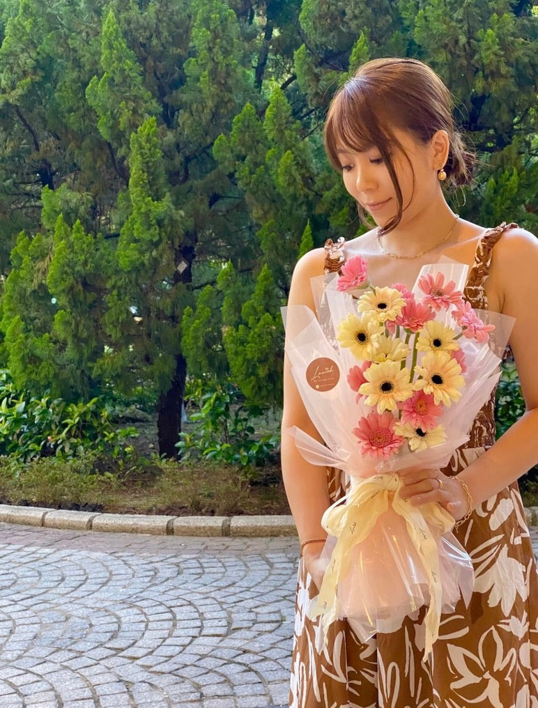 A clean product view of the "Pink Gerbera Dream" two-tone Gerbera graduation bouquet by Lavish Florist, wrapped in pastel pink paper, ideal for little graduates.