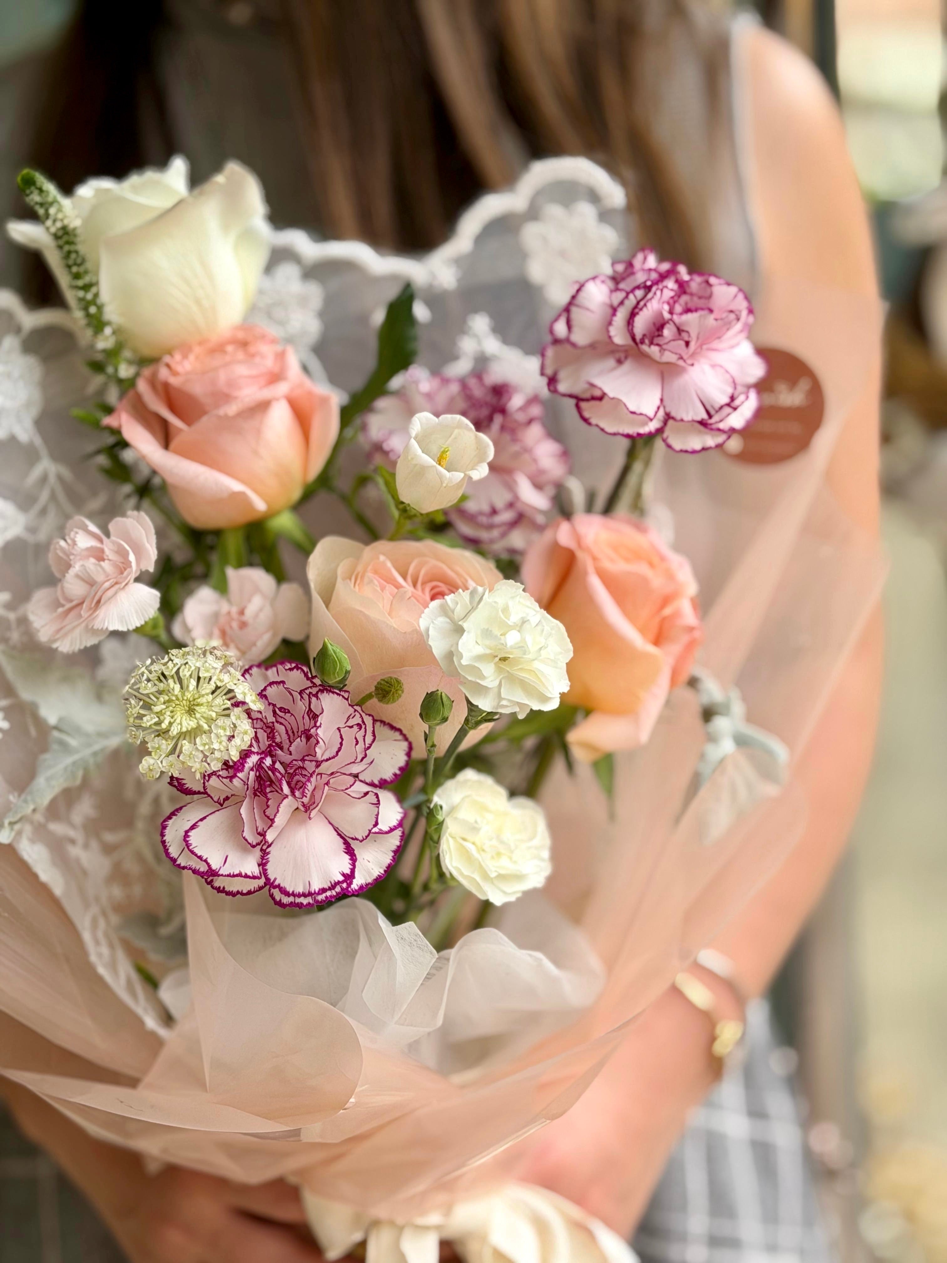 Bouquet of flowers held by a person wearing a lace dress.