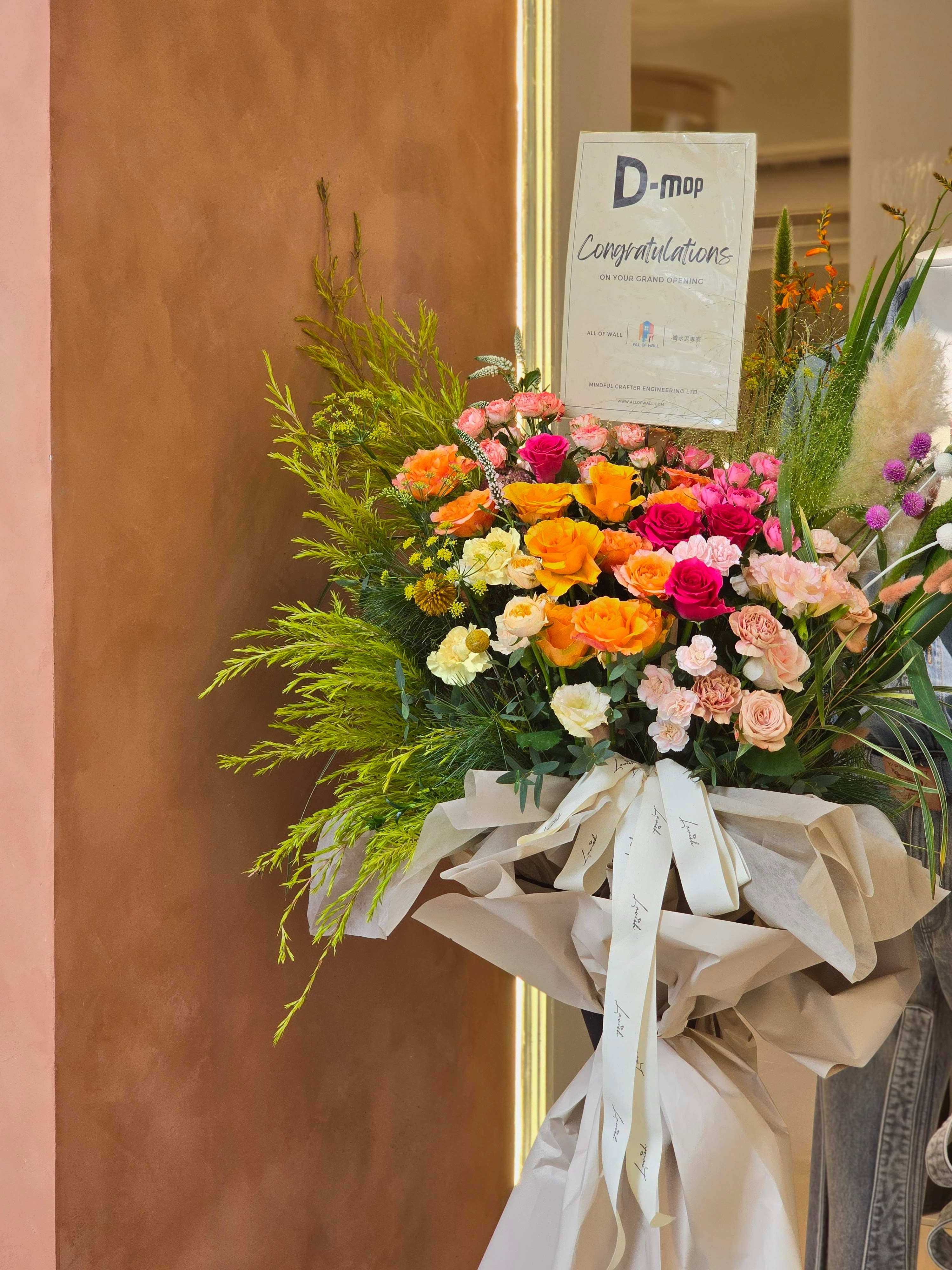 Vibrant grand opening flower basket in pink, orange, yellow and white with lush green foliage, designed for D-mop's store opening, Lavish Florist