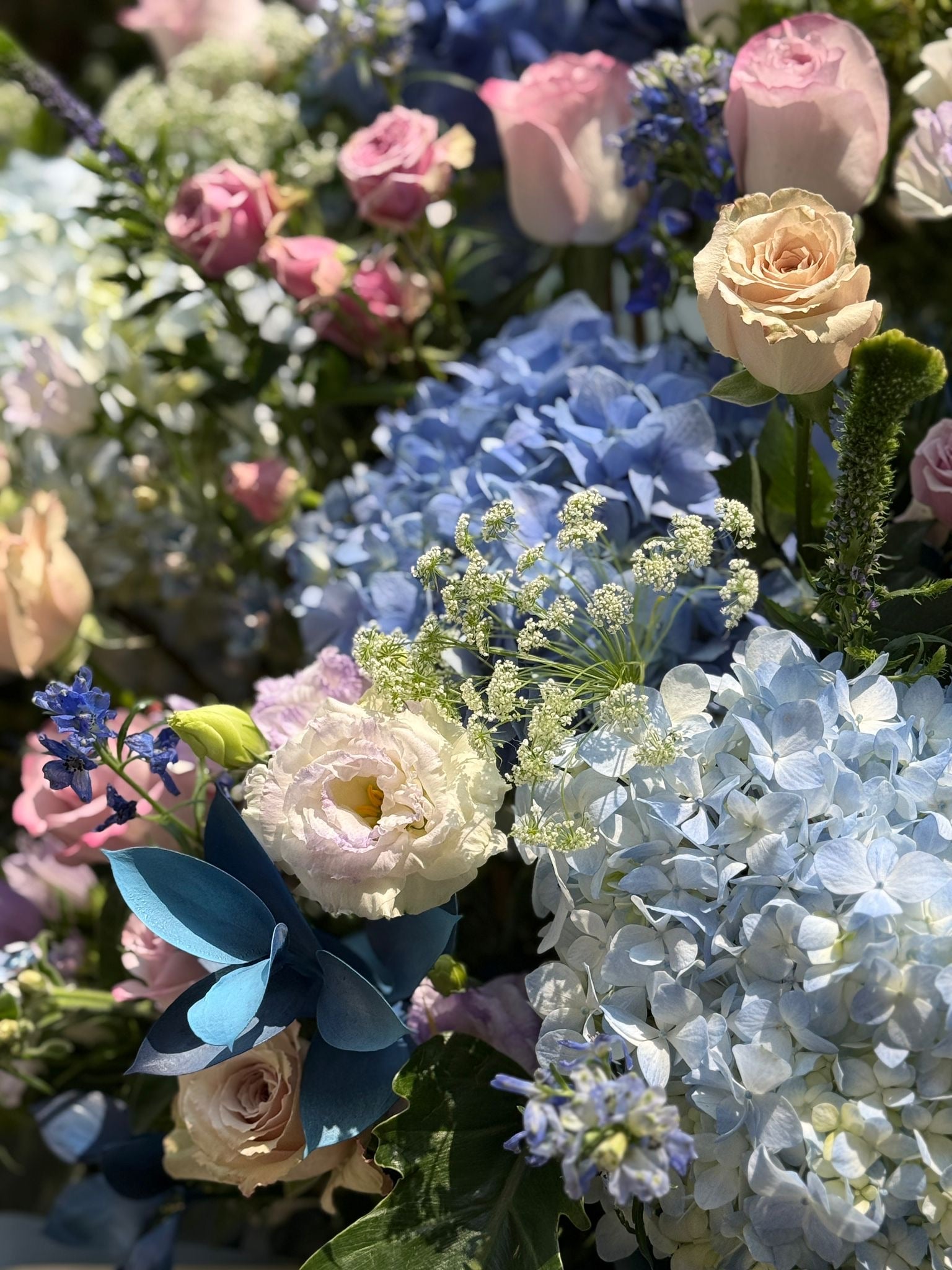 A classic-sized French country style grand opening flower stand called "Laurel Fleur Meadow" designed by Lavish Florist,  featuring a luxurious arrangement of royal blue and light blue hydrangeas, pastel pink roses, and white Canterbury bells in Morandi blue wrapping paper—the perfect premium grand opening flower basket for trendy cafe and boutique shop launches.